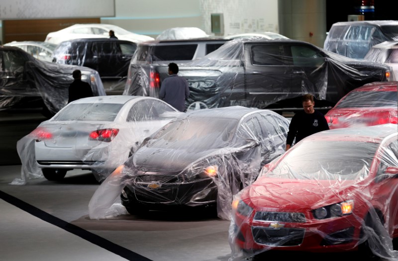 © Reuters. FILE PHOTO -  Vehicles are covered with protective wrap as workers prepare the General Motors automakers display ahead of the media preview of the North American International Auto Show in Detroit