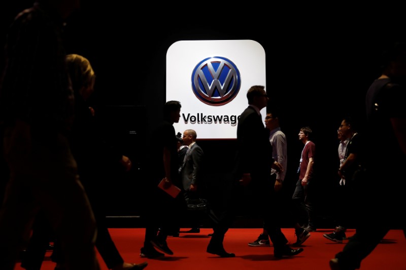 © Reuters. Pessoas passam em frente a logo da Volkswagen em evento em Xangai, na China