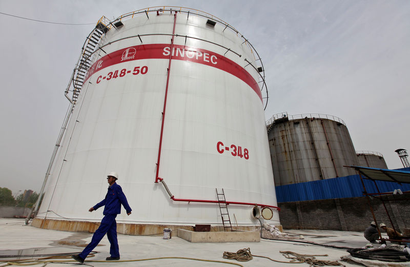 © Reuters. FILE PHOTO: An employee walks past oil tanks at a Sinopec refinery in Wuhan, Hubei province