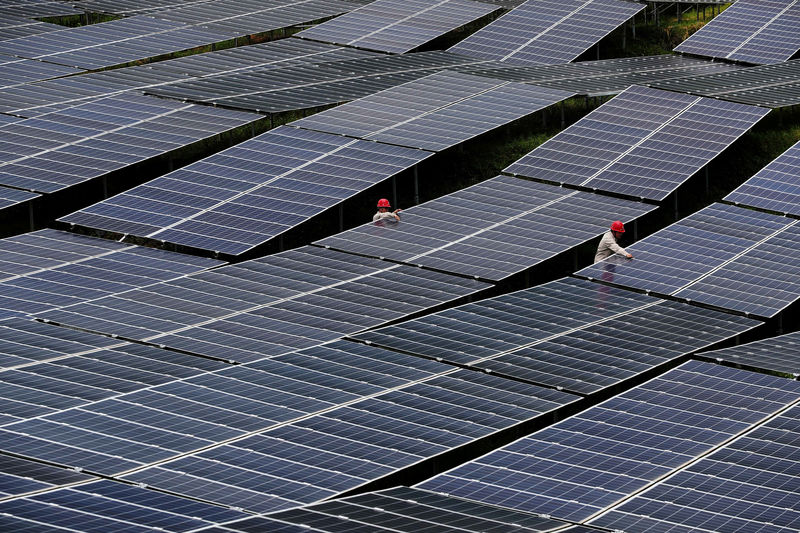 © Reuters. FILE PHOTO: Workers check solar panels at a photovoltaic power station in Chongqing