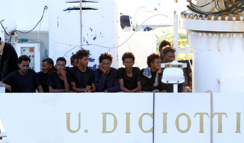 © Reuters. Migrants wait to disembark from the Italian coast guard vessel "Diciotti" at the port of Catania