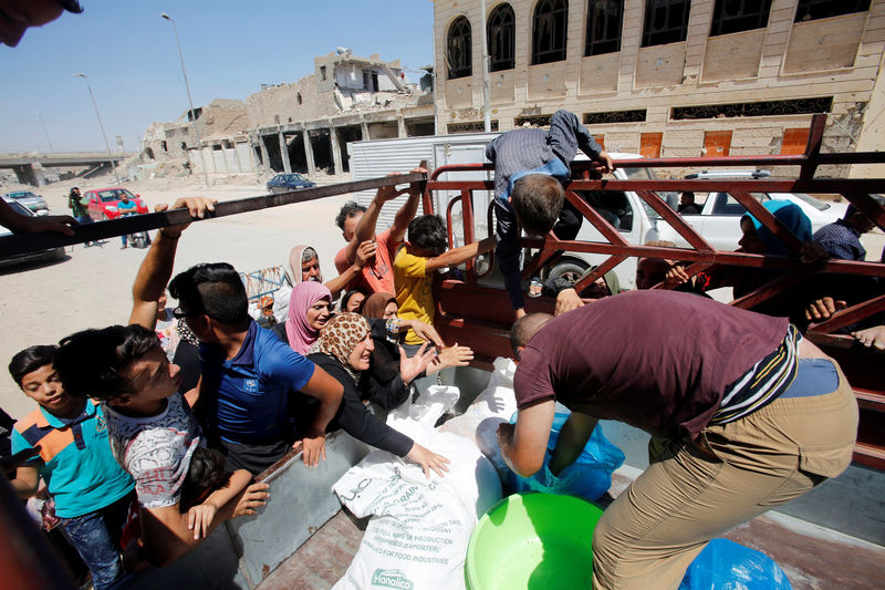 © Reuters. Citizens gather around a car that distribute meat for the poor families in the old city of Mosul