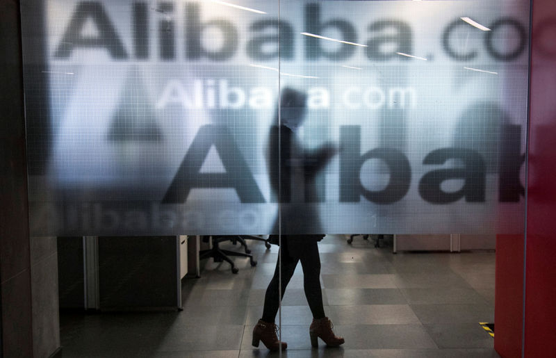 © Reuters. FILE PHOTO: An employee is seen behind a glass wall with the logo of Alibaba at the company's headquarters on the outskirts of Hangzhou, Zhejiang province