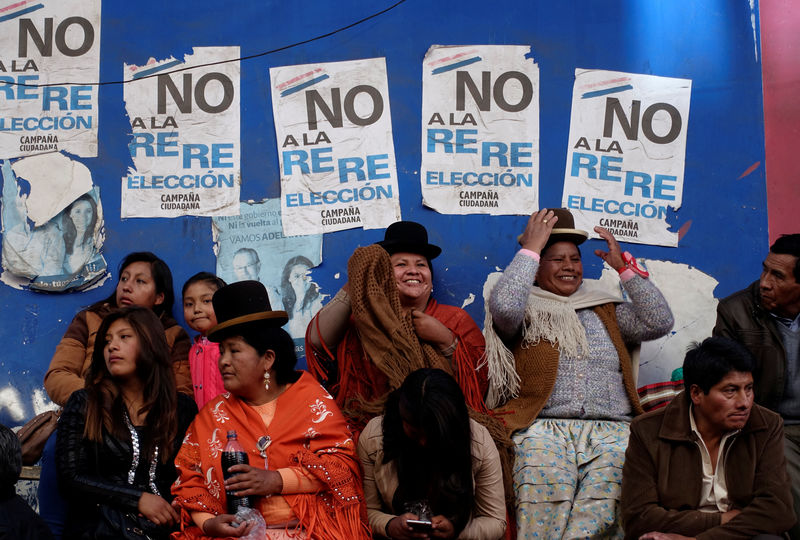 © Reuters. La gente se sienta frente a carteles contra el intento del presidente boliviano, Evo Morales, de reelegirse en 2019, en La Paz