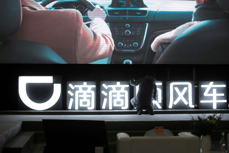 © Reuters. FILE PHOTO: Man is seen in front of a Didi sign before a promotional event of its Hitch service for the Spring festival travel rush, in Beijing