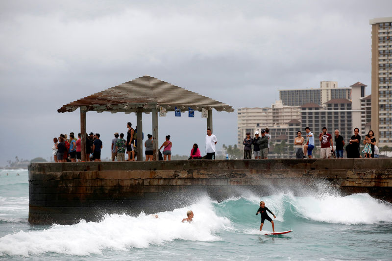© Reuters. Turistas miran a los surfistas en Waikiki Bay mientras la tormenta tropical Lane se aproxima a Honolulu, Hawái, EEUU.