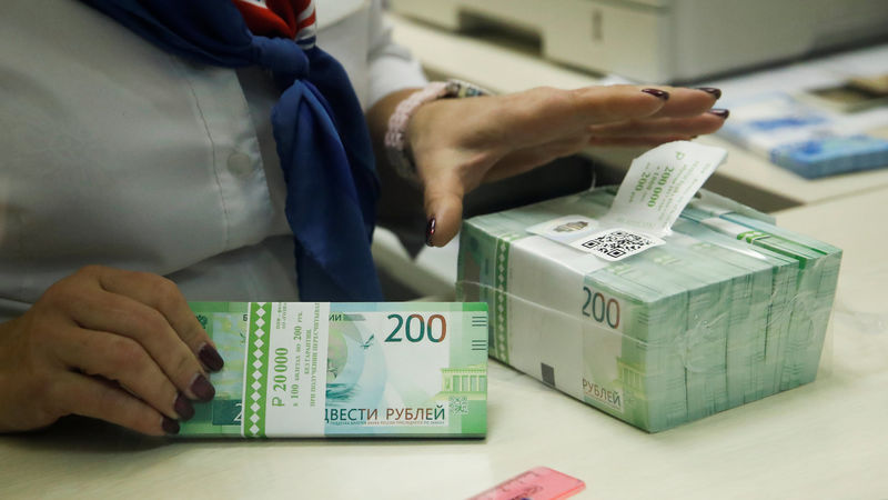 © Reuters. FILE PHOTO: A cashier holds new 200 rouble banknotes in a bank in Moscow
