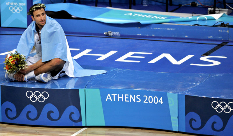 © Reuters. FILE PHOTO: Argentine basketball player Ginobili sits on the podium after winning the gold medal in Athens.