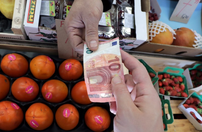 © Reuters. A customer pays a fruit merchant on a market in Nice