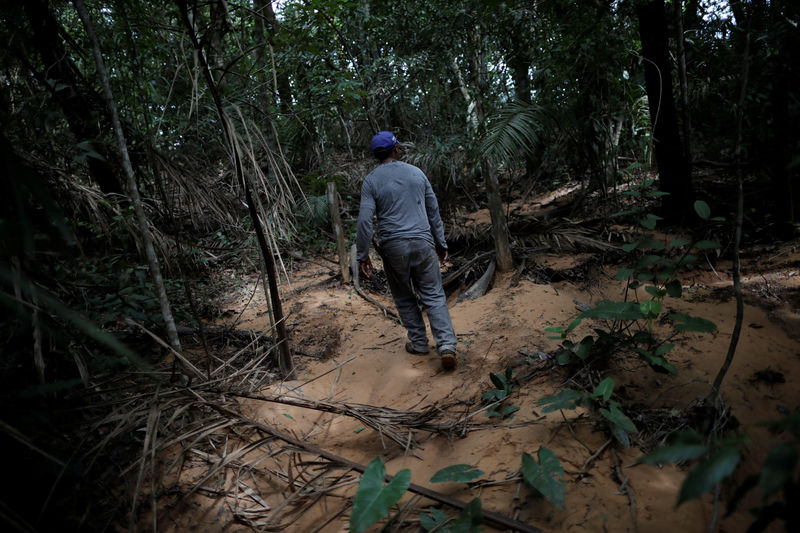 © Reuters. Subsistence farmer Valdineiz Pereira walks on sand that has invaded spring water inside of area of cerrado in a farm near Barra do Ouro