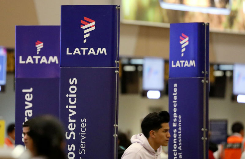 © Reuters. Passengers walk near the LATAM airlines counter at Jorge Chavez airport in Callao