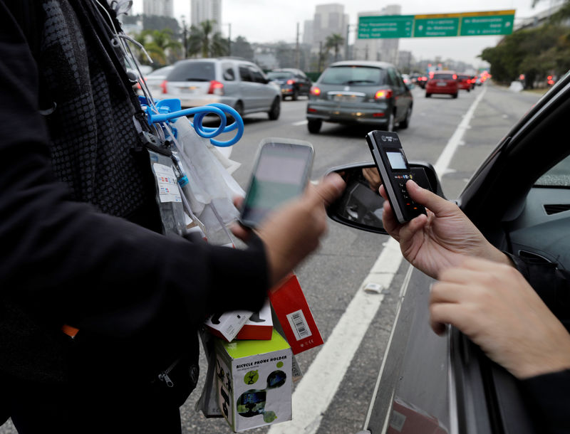 © Reuters. Vendedor ambulante recebe pagamento com cartão de crédito de um motorista durante a hora do rush em uma das principais vias de São Paulo