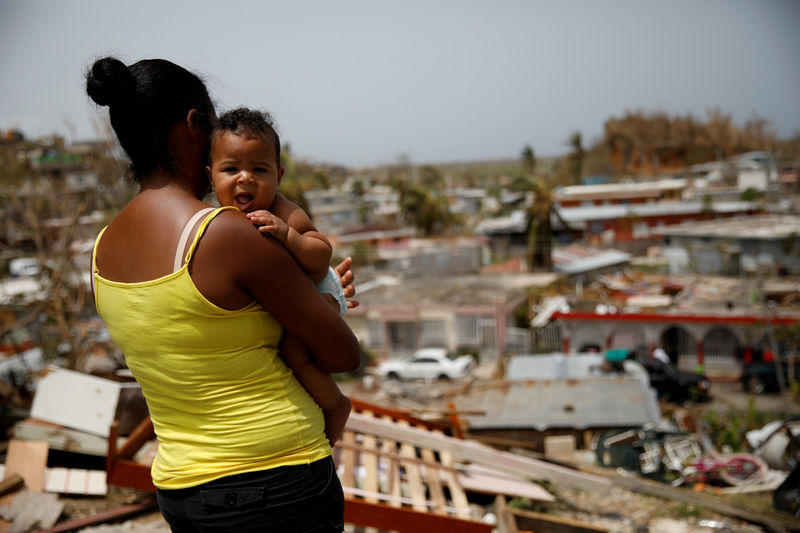 © Reuters. FILE PHOTO:    Ysamar Figueroa carrying her son Saniel, looks at the damage in the neighbourhood after the area was hit by Hurricane Maria, in Canovanas