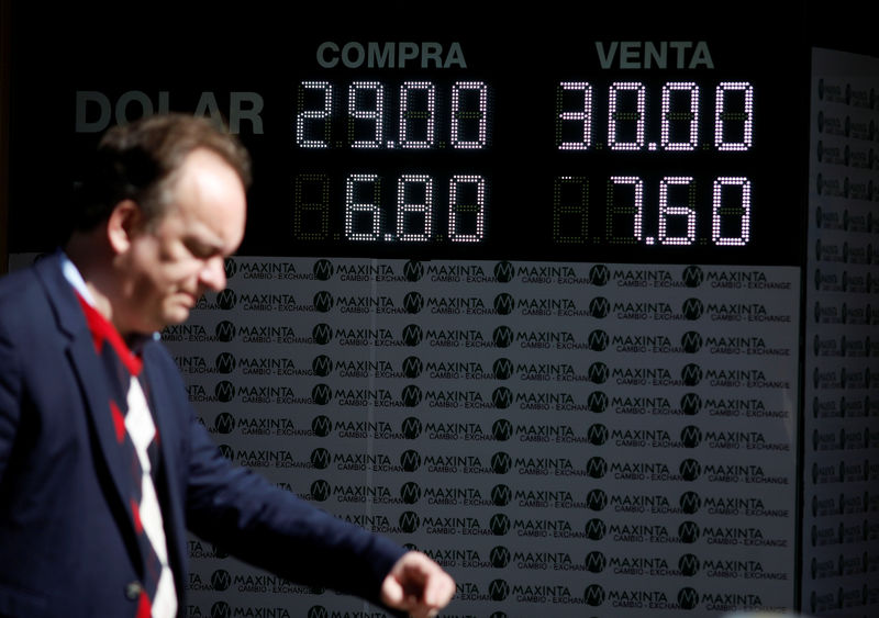 © Reuters. Homem passa por paínel eletrônico de cotação em Buenos Aires, Argentina