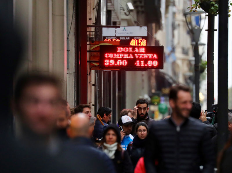 © Reuters. People walk past a currency exchange board in Buenos Aires' financial district