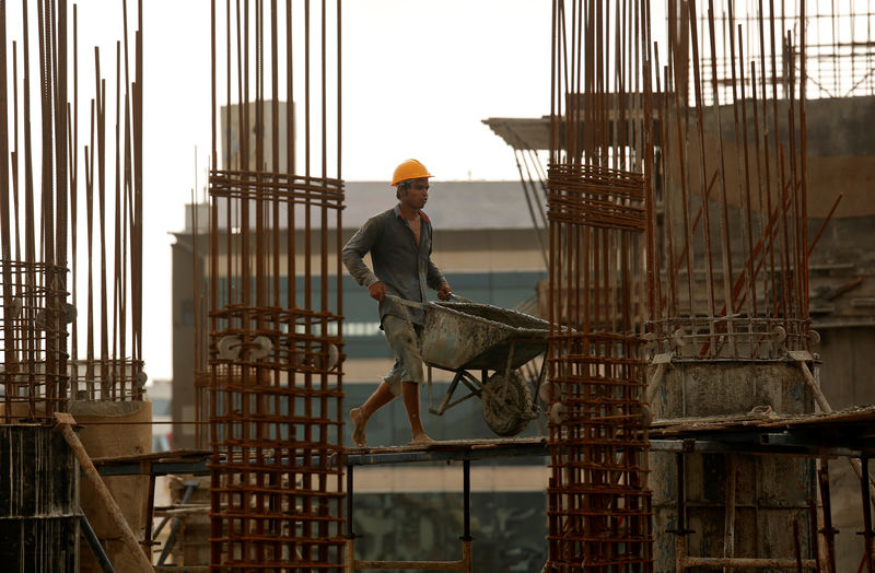 © Reuters. A worker pushes a wheelbarrow to collect cement at a construction site of a residential building in Mumbai