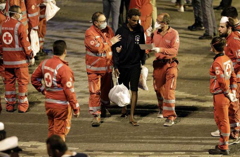 © Reuters. A migrant is helped by Red Cross memebrs after disembarking from Italian coast guard vessel "Diciotti" at the port of Catania