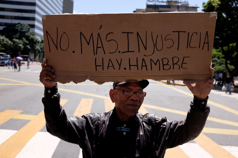 © Reuters. Un hombre sostiene una pancarta que dice "No más injusticia. Hay hambre" durante una protesta de jubilados en Caracas por sus pensiones.