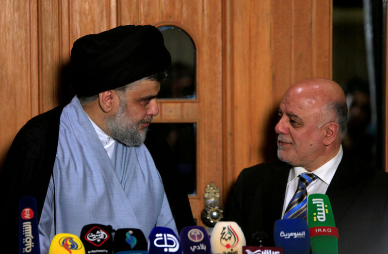 © Reuters. FILE PHOTO: Iraqi Shi'ite cleric Moqtada al-Sadr, who's bloc came first, looks at Iraqi Prime Minister Haider al-Abadi, who's political bloc came third in a May parliamentary election, during a news conference in Najaf