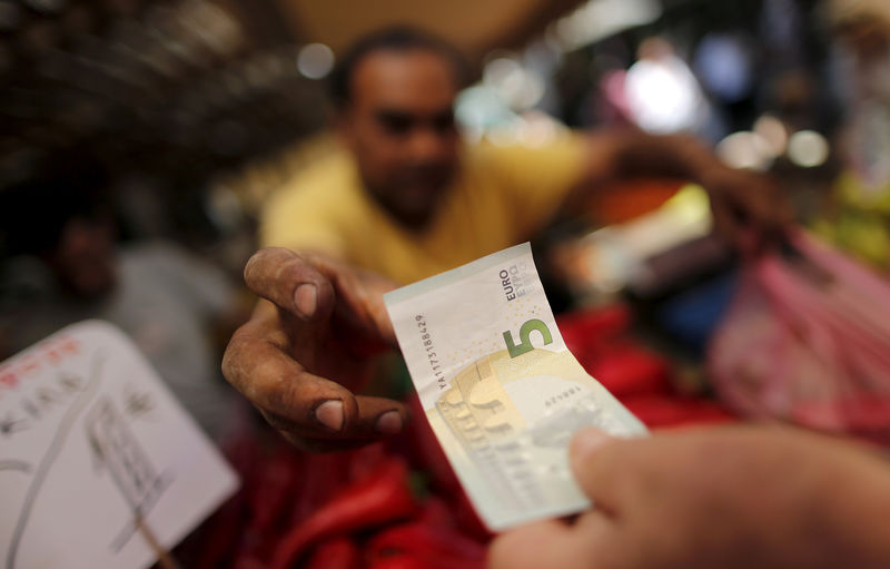 © Reuters. A vendor gets a five Euro bank note from a customer at the central market in Athens