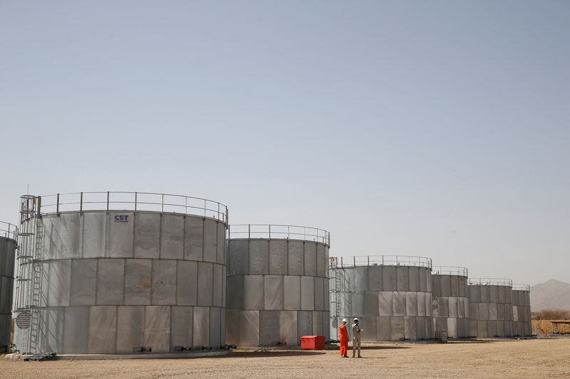 © Reuters. FILE PHOTO: Workers walk past storage tanks at Tullow Oil's Ngamia 8 drilling site in Lokichar