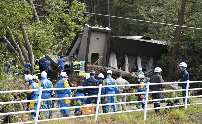 © Reuters. Police officers and rescue workers search for survivors from a building damaged by a landslide caused by a powerful earthquake in Atsuma town