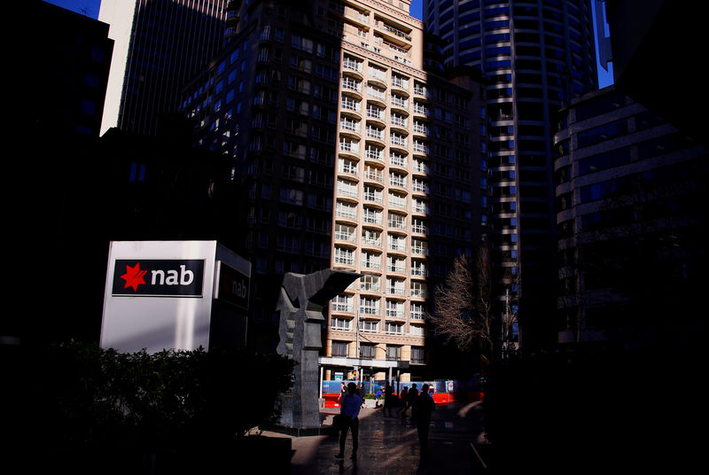 © Reuters. FILE PHOTO: Pedestrians walk past the logo of National Australia Bank which is displayed outside their headquarters building in central Sydney