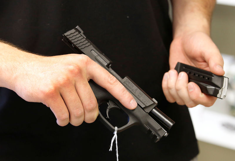 © Reuters. A salesman holds a Smith & Wesson handgun and magazine at the "Ready Gunner" gun store in Provo