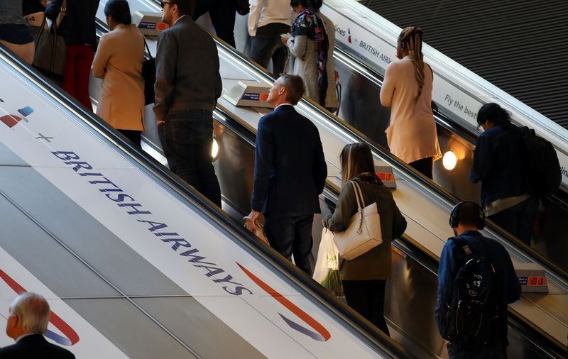 © Reuters. Commuters pass a British Airways advert on the tube at Canary Wharf