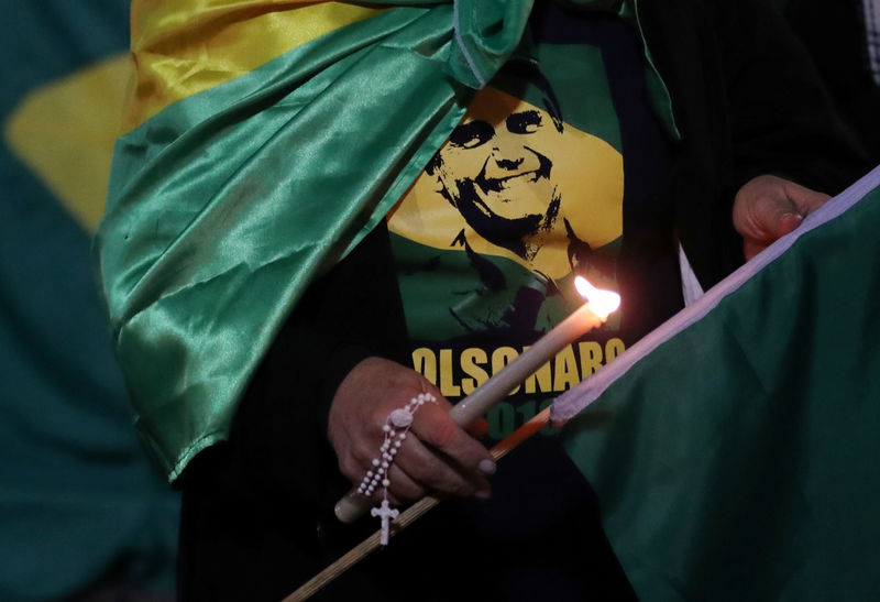 © Reuters. FILE PHOTO - A woman lights a candle for presidential candidate Jair Bolsonaro after he was stabbed by a man in Juiz de Fora at Paulista avenue in Sao Paulo