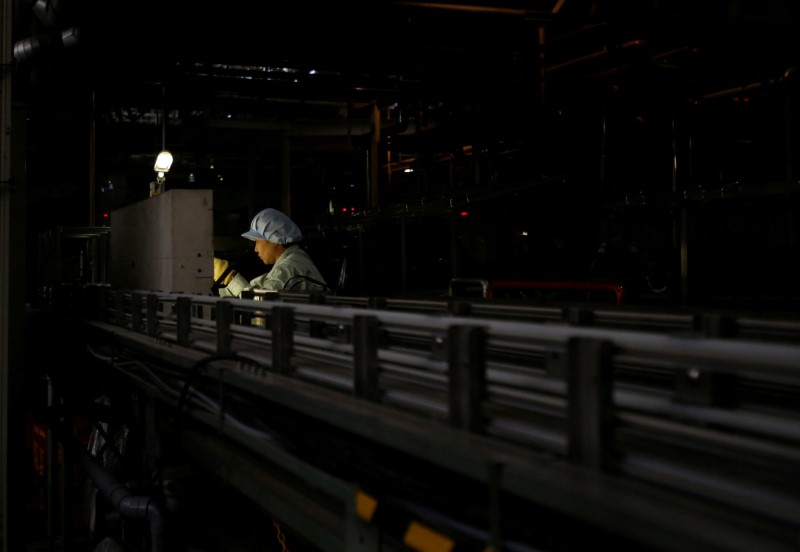 © Reuters. FILE PHOTO - An employee works at a beer production line at a factory in Toride