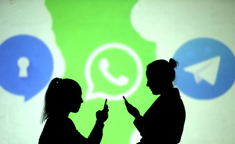 © Reuters. Pessoas utilizam celulares diande de projeção dos logos do Signal, WhatsApp e Telegram em foto ilustrativa