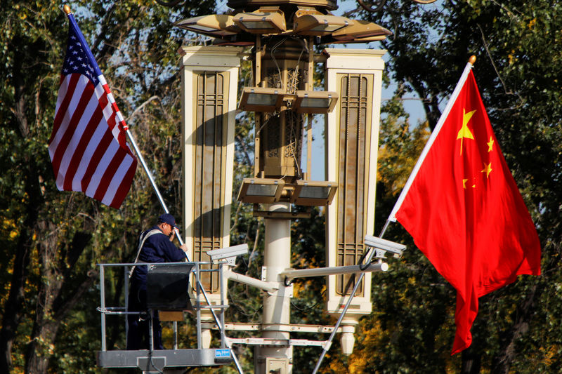 © Reuters. FILE PHOTO: A worker places U.S. and China flags near the Forbidden City ahead of a visit by U.S. President Donald Trump to Beijing, in Beijing