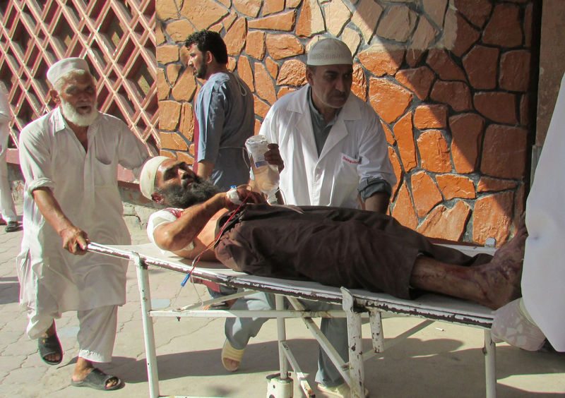 © Reuters. Afghan men carry an injured man to a hospital after a suicide attack in Nangarhar province