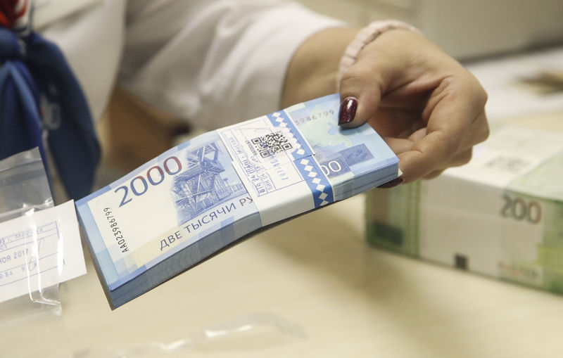 © Reuters. A cashier holds new 2,000 rouble banknotes in a bank in Moscow