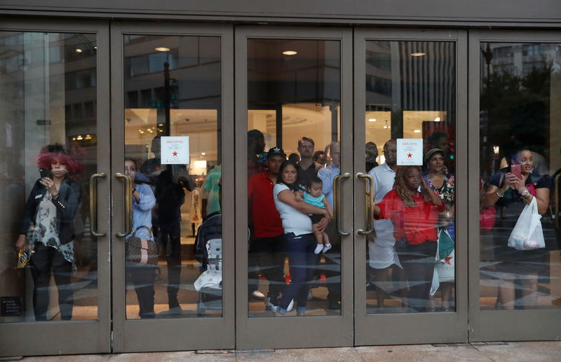 © Reuters. People observe from inside a Macy's department store as opponents of a white nationalist-led rally marking the one-year anniversary of the 2017 Charlottesville "Unite the Right" protests, march in downtown Washington