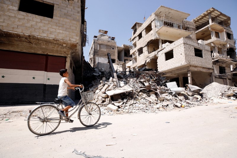 © Reuters. Menino passa por rua danificada em Kafr Batna, em Ghouta, na Síria