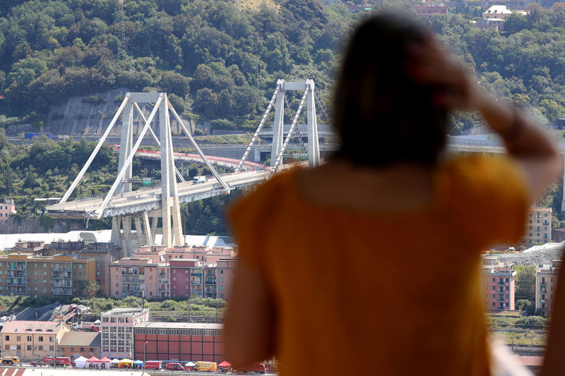 © Reuters. FILE PHOTO: A woman looks at the collapsed Morandi Bridge, in the port city of Genoa