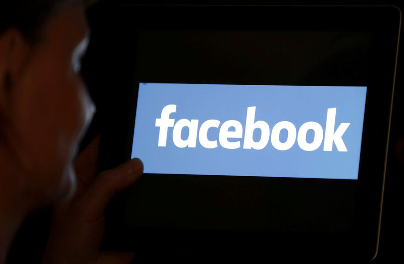© Reuters. A woman looks at the Facebook logo on an iPad in this photo illustration