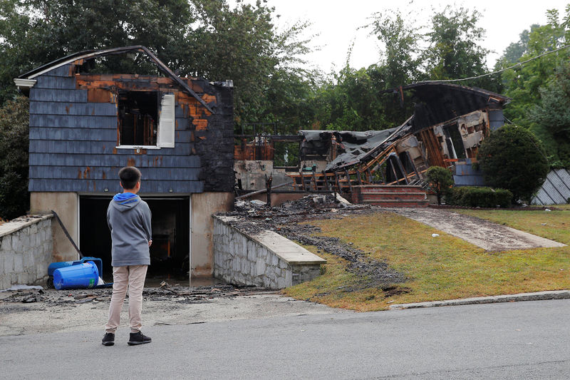 © Reuters. A neighbor looks at a home burned in a series of gas explosions in Lawrence