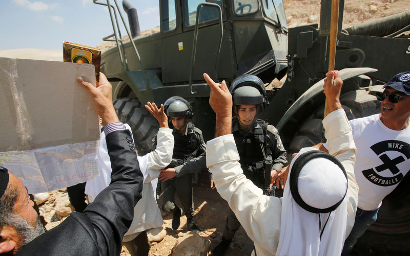 © Reuters. سكان الخان الأحمر يحاولون منع جرافة إسرائيلية من إغلاق الطرق المحيطة