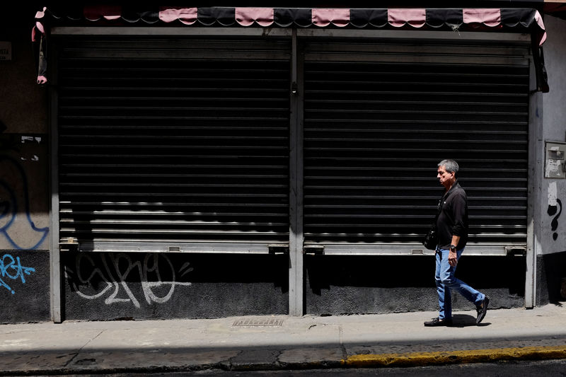 © Reuters. A man walks past closed stores in Caracas