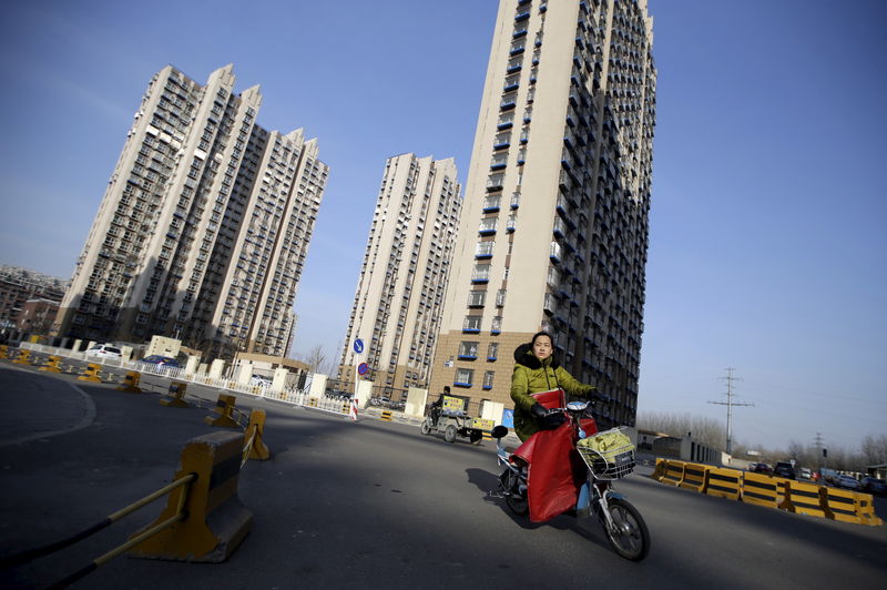 © Reuters. A woman rides past a residential compound in Beijing's Tongzhou district