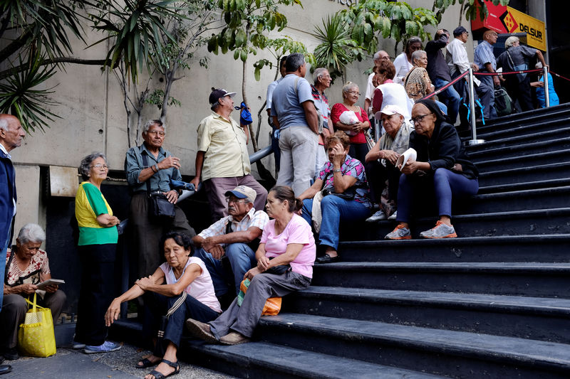 © Reuters. Venezolanos hacen largas filas para cobro de salario mínimo mientras empresas luchan por pagar