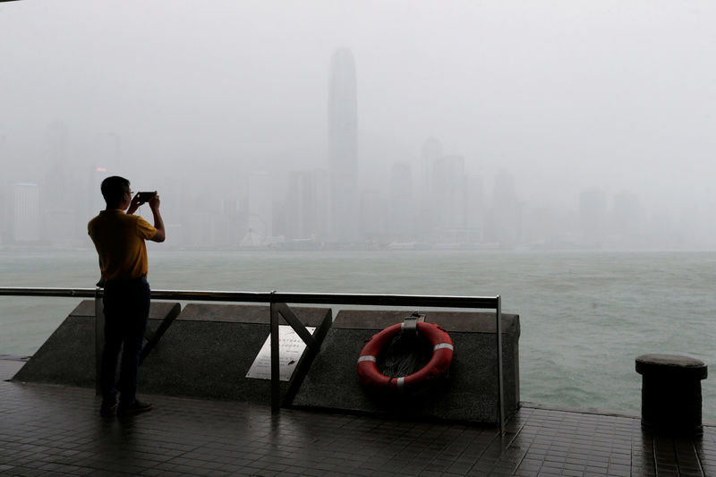 © Reuters. A man takes a photo on the waterfront while heavy rains fall on Victoria Harbour as Typhoon Mangkhut approaches Hong Kong