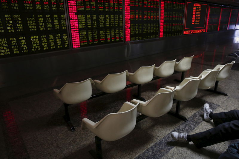 © Reuters. A man's legs are pictured as he looks at an electronic board showing stock information is pictured at a brokerage house in Beijing