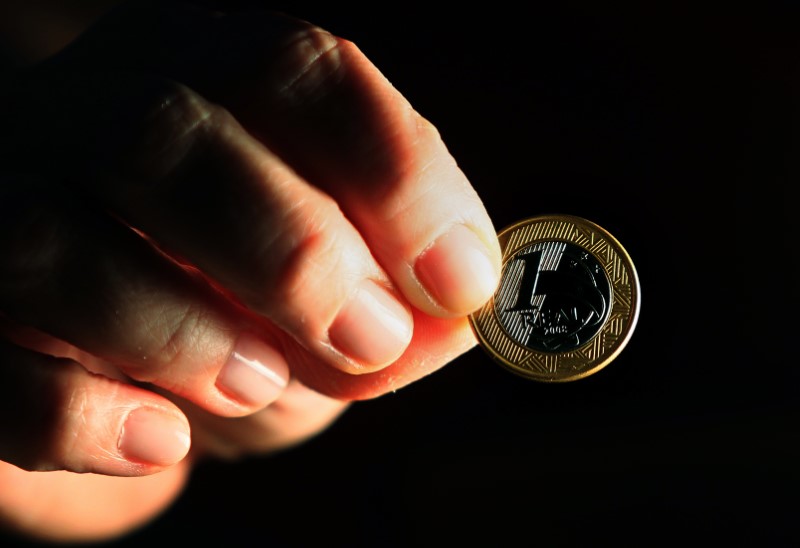 © Reuters. Pessoa segura moeda de um real em foto ilustrativa