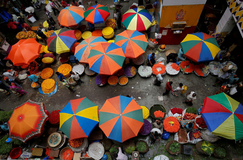 © Reuters. FILE PHOTO: Vendors sit under umbrellas inside a wholesale flower market in Bengaluru
