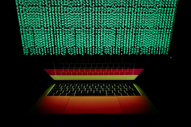 © Reuters. FILE PHOTO: German flag is seen on the laptop screen in front of a computer screen on which cyber code is displayed, in this illustration picture