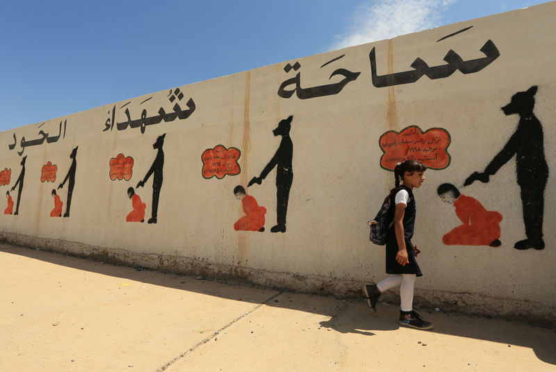© Reuters. An Iraqi student walks past a school wall covered with drawings showing how Islamic State militants executed their prisoners in Mosul